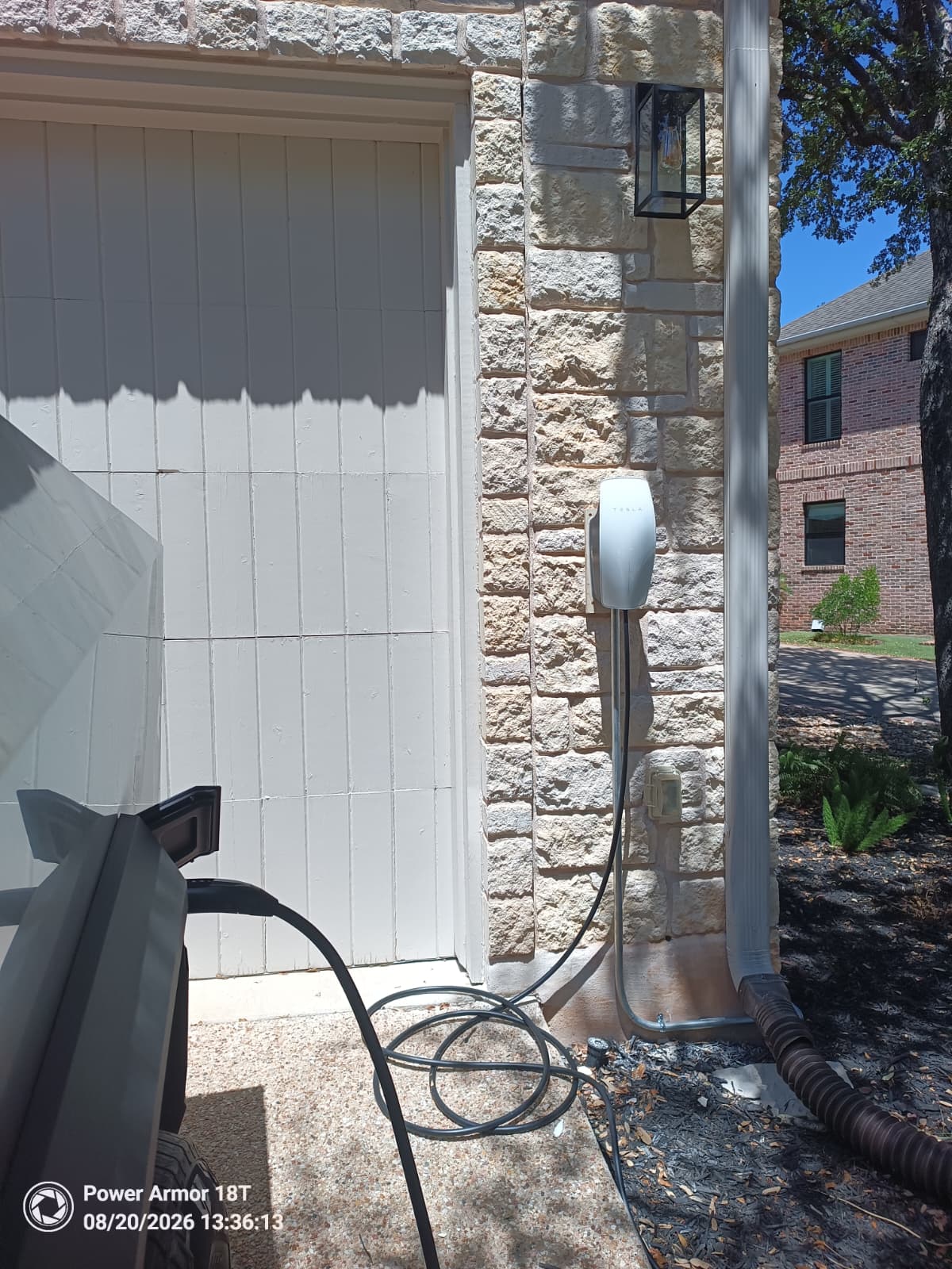 Tesla Wall Connector installed beside a stone garage entrance